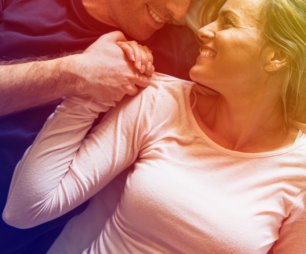 Middle-aged couple holding hands and smiling at home, a common context for erectile dysfunction concerns